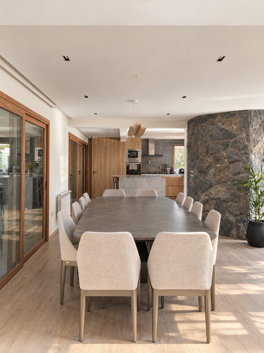 Comedor con mesa de madera y muro de piedra, Remodelación en Jockey Club