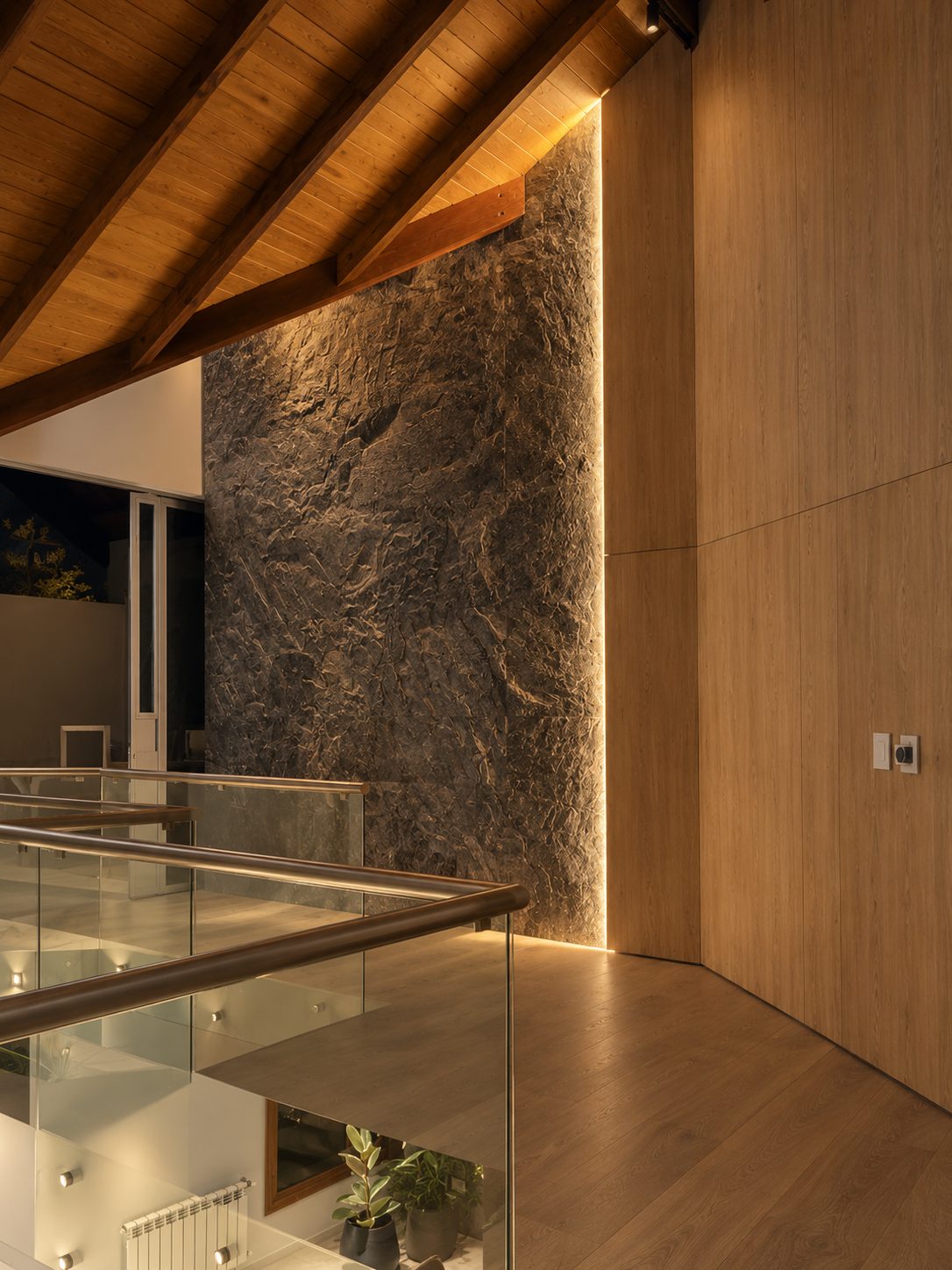 Escalera de madera y vidrio junto a muro de piedra, Remodelación en Jockey Club