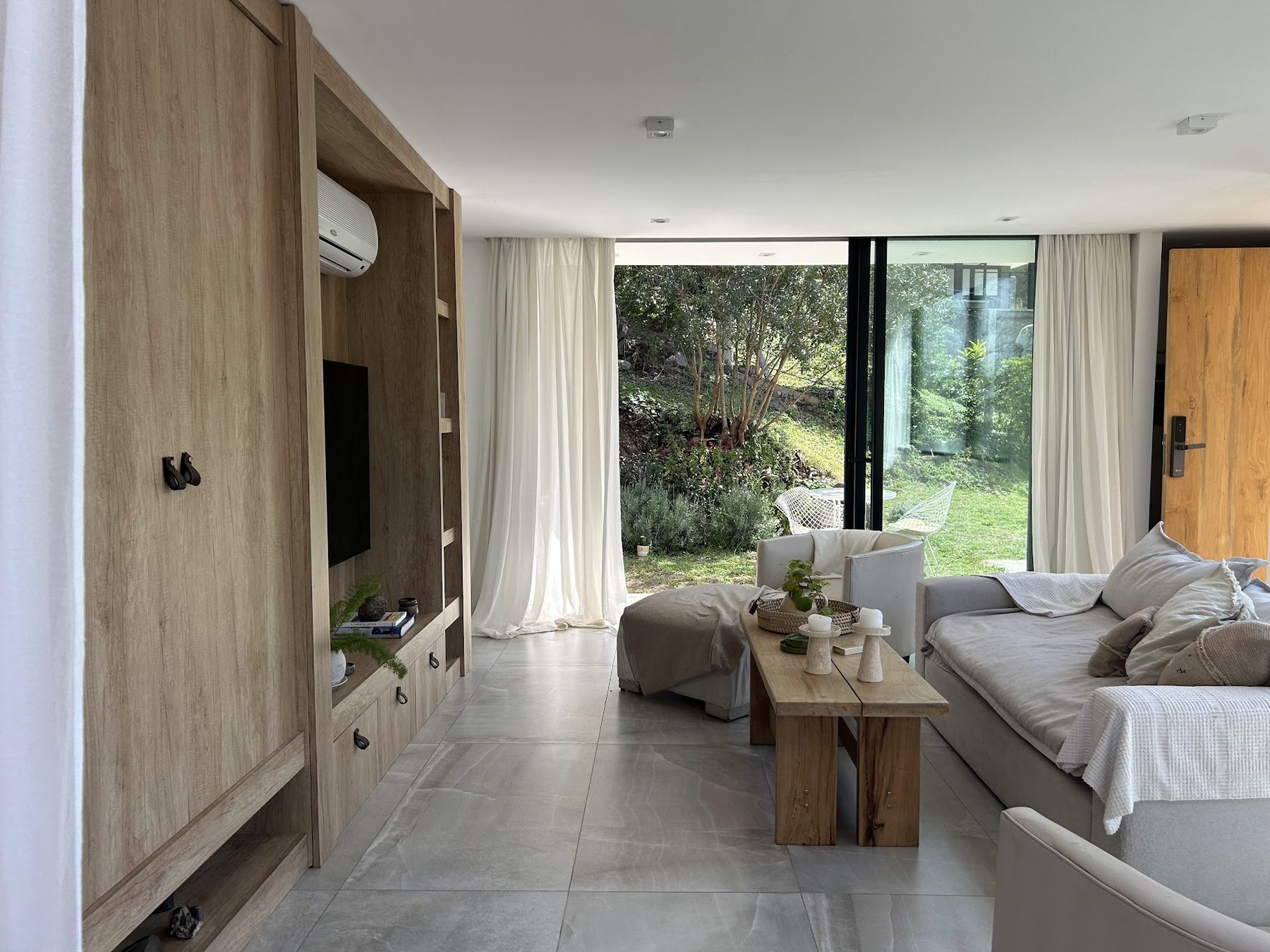 Living con ventanales y sofá, Casa con ventanal plegable en la sierra